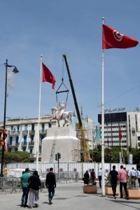 A picture taken on May 23, 2016 shows people walk past the statue of Tunisia's first president, Habib Bourguiba, on a horse from La Goulette, upon relocating it back to its original location in central Tunis.  / AFP / FETHI BELAID